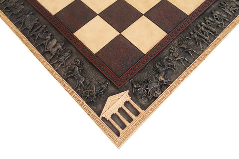 Šachmatų lenta – artimas kampo kadras su rudos–kreminės langeliais ir detaliu antikinių karo vežimų bei templio reljefu