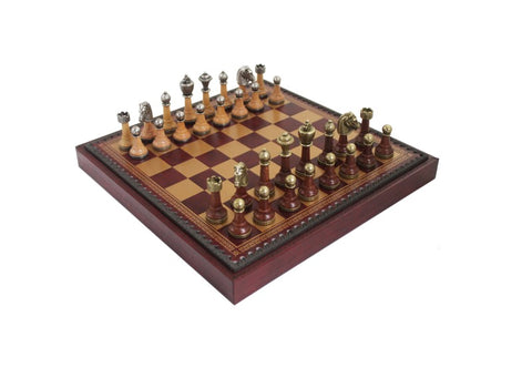 Šachmatų rinkinys išraizgyta riešuto ir raudonmedžio lentos su metalinėmis karūnuotomis figūromis ir dekoruotu bortu, žvelgiant iš kampo