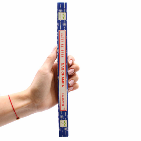 Nag Champa smilkalai, mėlynoje ilgoje pakuotėje, rankoje parodytas dydis ir nešiojimo mastelis