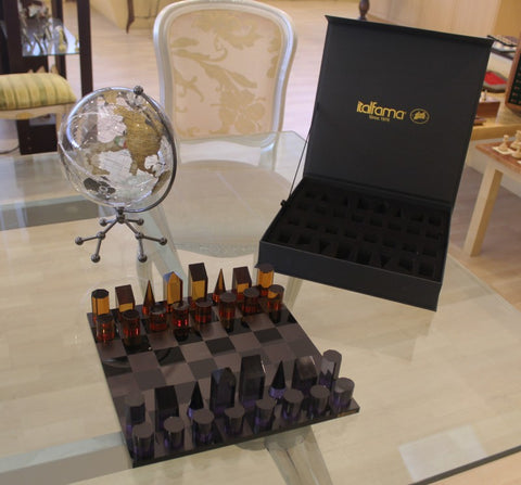 Šachmatų rinkinys Italfama su blizgia juoda lenta ir gintaro bei violetinėmis geometrinėmis figūrėlėmis, pristatomas su atvira juoda laikymo dėže