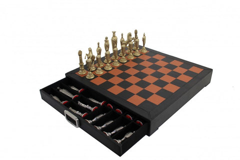 Šachmatai odos imitacijos rudos‑juodos lentos su ištraukiama dėžute ir auksinėmis bei sidabrinėmis figūromis, rodoma iš šono