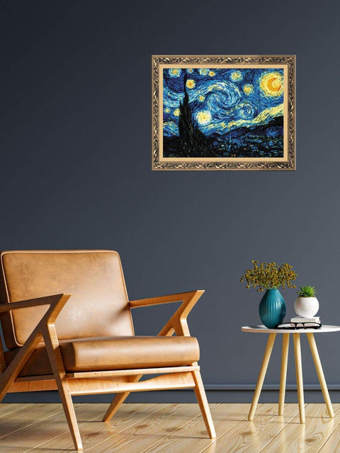 Sieninis paveikslas Starry Night su auksine ornamentuota rėme, kraštovaizdžio orientacijos, kabantis virš odinio fotelio interjere