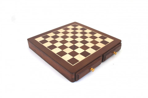 Šachmatų lenta iš tamsaus ir šviesaus medžio, uždaryta, nufotografuota kampu su dviem stalčiukais ir auksinėmis rankenėlėmis