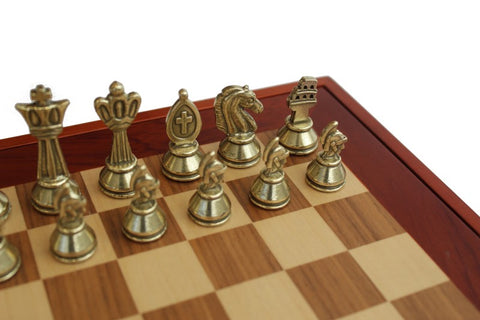 Šachmatai — aukso spalvos metalinės figūros ant medinės lentos kampo, elegantiškas kolekcijos komplektas