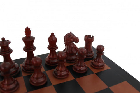 Šachmatų rinkinys – tamsiai raudonos medinės figūros ant rudai juodos lentos, arti kadro matomas raitelis ir pėstininkai