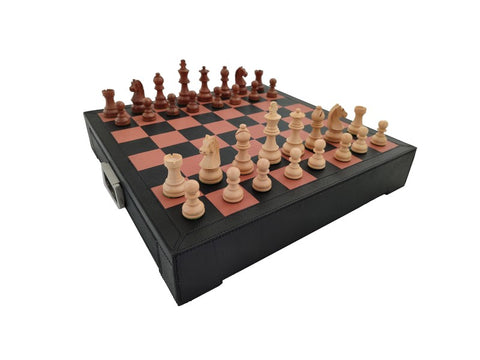 Šachmatai ant raudonai‑juodos odinės dėžės su šviesiomis ir tamsiomis medinėmis figūromis, paruošti žaidimui iš kampo