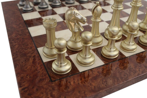Šachmatų rinkinys su auksinėmis figūromis ant riešutinio ąžuolo lentos kampo, artimas planas rodantis raitelį ir pėstininkus