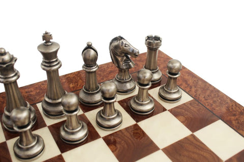 Šachmatų komplektas: sidabrinės metalinės figūros ant tamsios riešuto lentos, artimas kampinis planas su karaliumi, riteriu ir bokštu