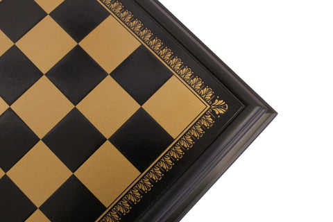Šachmatų lenta juodos ir aukso spalvos, kampinis arti priartinimas parodo dekoratyvų auksinį raštą ir tamsų medinį rėmą