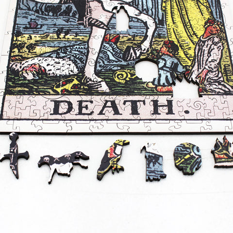 Dėlionė „Death“ teminė artimas kadras, matomi unikalūs mediniai formos gabalėliai – kardas, šuo, papūga, kaukolė