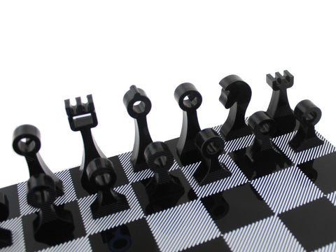 Šachmatai su moderniomis juodomis akrilinėmis figūromis, artimas planas ant juodai baltos raštuotos lentos
