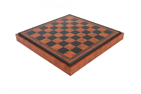 Šachmatų lenta rudos–juodos spalvos odinės apdailos su dekoratyvia iškilia kraštine, rodoma pasvirusiu kampu