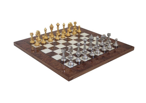 Šachmatų rinkinys su tamsia riešutmedžio lenta ir aukso bei sidabro metalinėmis figūromis, pateiktas pasvirusiu kampu