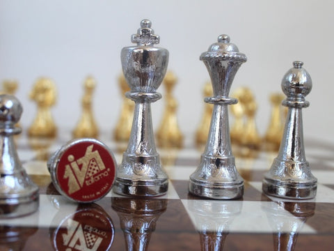 šachmatai: artimas planas sidabrinių karalienės, karaliaus ir pėstininko iš metalinio rinkinio, auksinės figūros fone