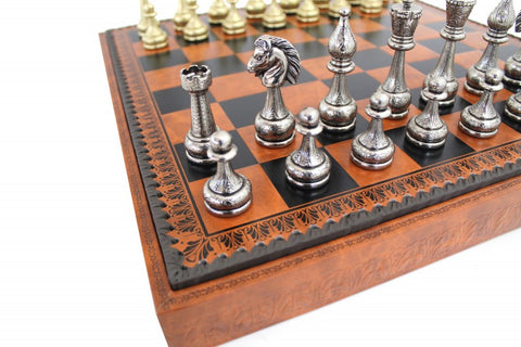 Šachmatai su sidabrinėmis figūromis ant intarsijuotos rudos medinės lentos, arti matomas ornamentuotas bortas