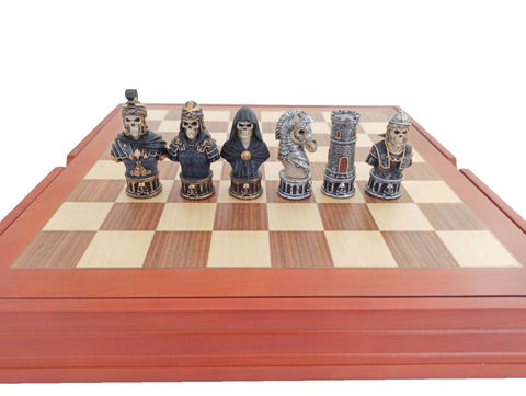 Šachmatų rinkinys su raudonu mediniu rėmu ir gotikinėmis skeletų figūromis, artimas priekinis planas