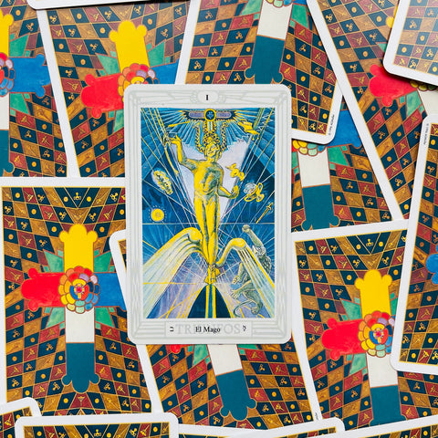 tarot korta „Magas“ – centrinė geltona figūra ant ryškaus mėlyno fono, rodoma iš arti ant kitų dekoruotų kortų fono