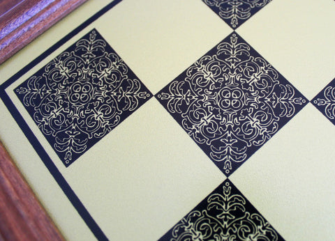 šachmatų lenta su kreminėmis ir tamsiai mėlynomis ornamentuotomis kvadratėmis, medinio rėmo kraštinė, artimas planas