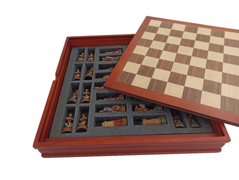 Šachmatai su raudonu mediniu rėmu ir nuimamu dangčiu; po lente putplasčio lizdai susidedančioms dažytoms figūroms