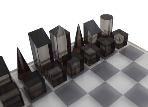 Šachmatų rinkinys su dūminio stiklo geometrinėmis figūromis ant matinės lentos, artimas kampinis planas