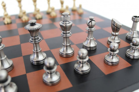 Šachmatai su sidabrinėmis metalinėmis figūromis ant rudos-juodos lentos, artimas karaliaus ir pėstininkų kompozicijos kadras