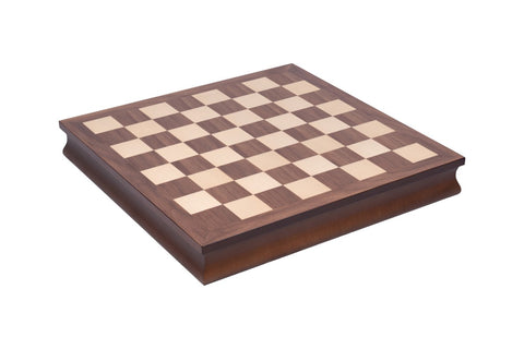 Šachmatų lenta tamsaus riešuto su šviesiomis kvadratėliais, pakeltas dekoratyvus medinis rėmas, kampinė perspektyva