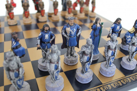 Šachmatų rinkinys — mėlynos ir sidabrinės viduramžių figūros ant juodo‑auksinio lentos, artimas kampo žvilgsnis