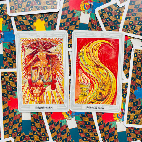 Tarot kortos — dvi atverstos ugninės Bastos kortos su ryškiomis raudono ir geltono tono iliustracijomis ant raštuoto fono