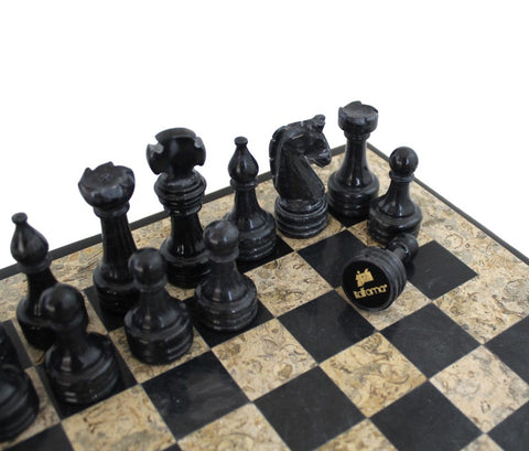 Šachmatų rinkinys juodos marmorinės figūros – arti planas ant juodai smėlinės lentos, nukritęs karalius su matomu logotipu