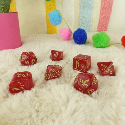 RPG kauliukai raudoni blizgūs su auksinėmis skaitmenimis, 7 vnt. rinkinys, d20 su katės simboliu ant pūkuoto fono
