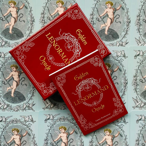 Lenormand kortų rinkinys Golden raudonoje dėžutėje su auksiniu tekstu, plokščias iš viršaus kompozicijos ant angelų iliustracijų fono