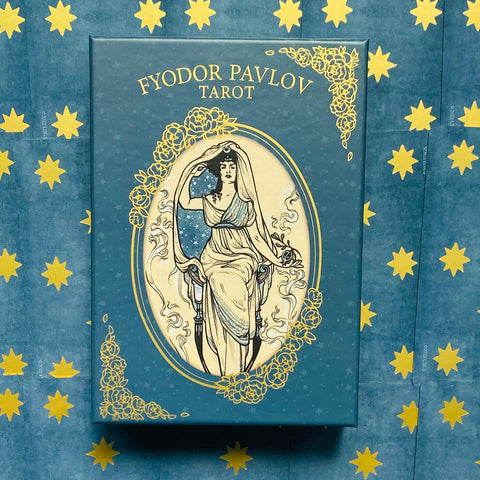 Fyodor Pavlov Tarot mėlynos ir auksinės dėžutė su moters iliustracija, fotografuota iš viršaus ant žvaigždėto fono