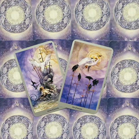 Tarot kortos pastelinių violetinių tonų denis su dviem atvertomis kortomis — Six of Swords ir Seven of Swords