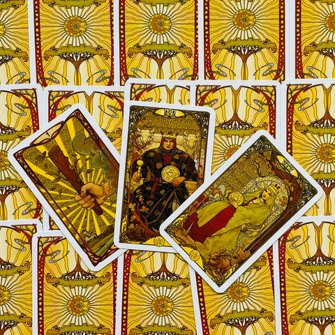 Tarot kortos su geltonai auksiniu nugarėlių raštu, trys atverstos kortos centre (pentakliai ir lazdelės), artimas kompozicinis variantas