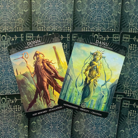 tarot kortos atviros dvi iliustruotos orakulų kortos Donn ir Danu ant žalio‑mėlyno geometrinio fono
