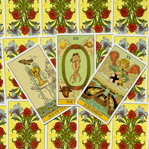 Tarot kortos Rider–Waite stiliaus, trijų kortų išdėstymas (The World, Judgement, Ace of Cups), geltoni gėlėti viršeliai, arti iš viršaus