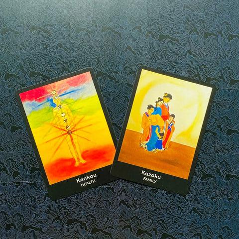 tarot kortos Kenkou (Sveikata) ir Kazoku (Šeima) plokščiai sudėtos ant tamsaus raštuoto fono, skirtos produktų galerijai