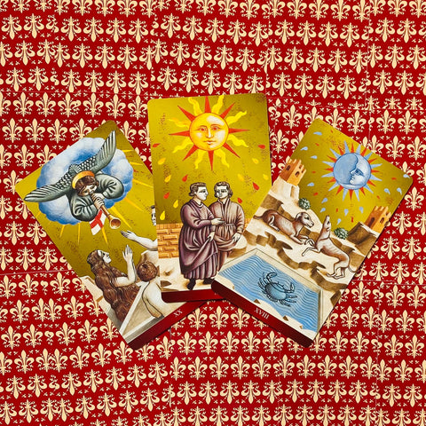 tarot kortos fanuotos trijų kortų rinkinys su saulės, mėnulio ir angelo iliustracijomis ant raudono ornamentuoto fono