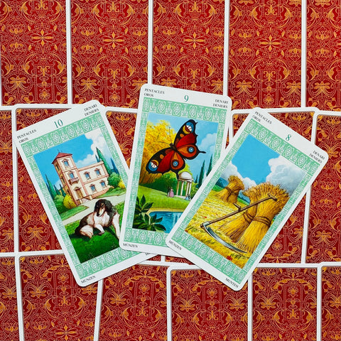tarot kortos Pentacles, trys žalti rėmeliai su atverstomis 8–10 kortomis ant raudono ornamentuoto nugarėlių fono