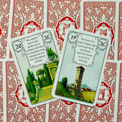 Lenormand kortos, dvi atverstos kortos (19 Bokštas ir 20 Sodas) ant raudonų ornamentuotų nugarėlių