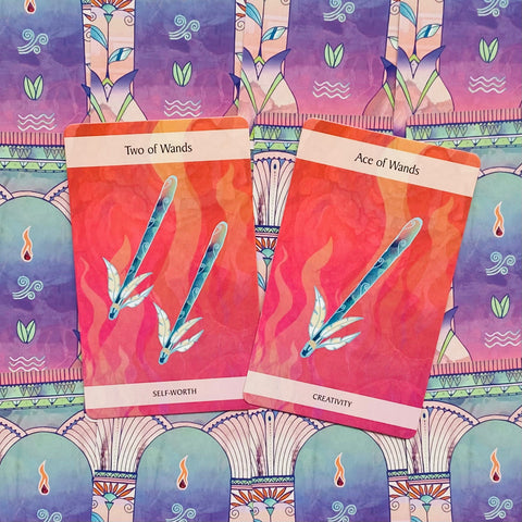 Tarot kortos, dvi rožinės rąstų kortos (Two of Wands – Self‑worth, Ace of Wands – Creativity) ant spalvingo fono