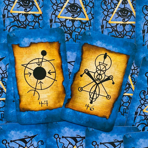 Tarot kortos su mėlynomis nugarėlėmis ir senovinio popieriaus centro sigilomis, aiškiai matomi numeriai 46 ir 47