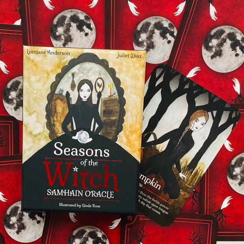 Kortų rinkinys Seasons of the Witch Samhain Oracle: dėžutės priekinis dangtis ir viena atversta korta su juodos suknios moterimi ant raudono mėnulio fono