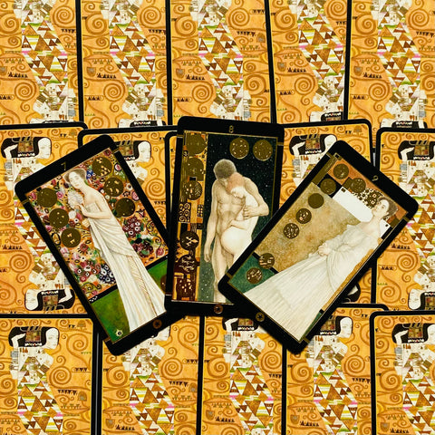tarot kortos Klimto stiliaus, trys atverstos kortos su auksinėmis detalėmis ant raštuotų auksinių nugarėlių