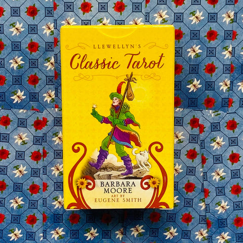Produkto nuotrauka – priekinis geltonas Classic Tarot dėžutės viršelis (Barbara Moore) iš priekio ant mėlyno gėlių fono