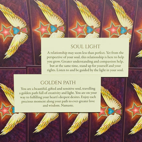 Orakulų kortos su violetiniais sparnų raštais, parodytos dvi atviros kortelės Soul Light ir Golden Path