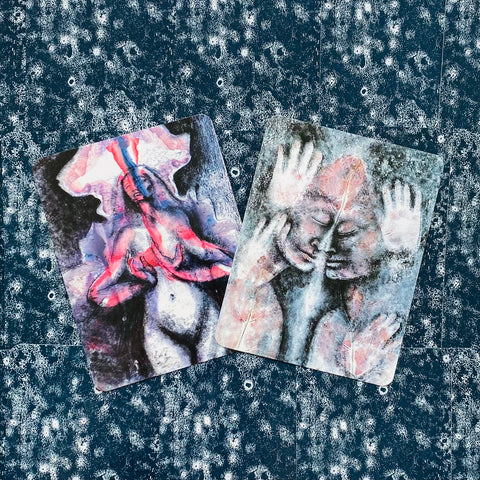 tarot kortos dvi abstrakčios iliustruotos kortos mėlyno‑rožinio atspalvio, padėtos persidengiančiai ant tekstūruoto fono