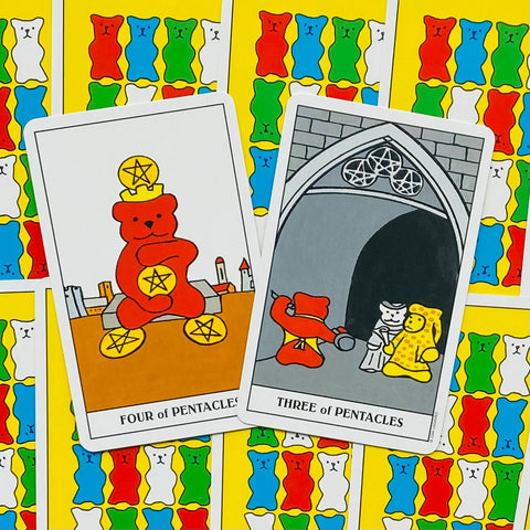 Tarot kortos su lokių motyvais, priekyje Keturi pentakliai ir Trys pentakliai, arti fotografuotos su ryškiu spalvotu lokių raštu fone