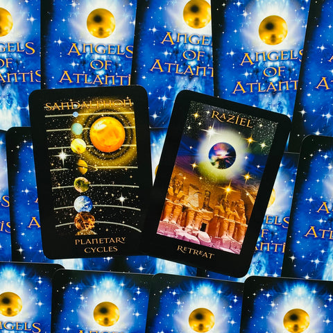 Orakulų kortos Angels of Atlantis mėlyname fone, dvi atverstos kortos (Planetary Cycles ir Retreat) prieš sluoksniuotas nugarėles