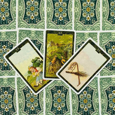 Tarot kortos trijų atvertų kortų išdėstymas ant žalios ornamentuotos nugarėlės, rodantis iliustracijas ir meninį dizainą